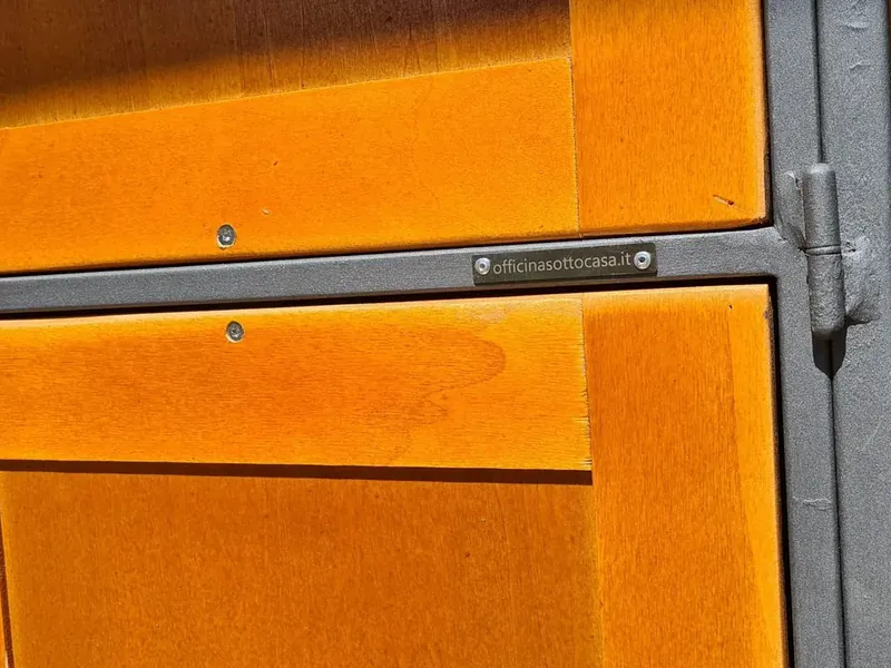 Anta dell'armadio da giardino in legno arancione con telaio in ferro grigio e targhetta officinasottocasa.it