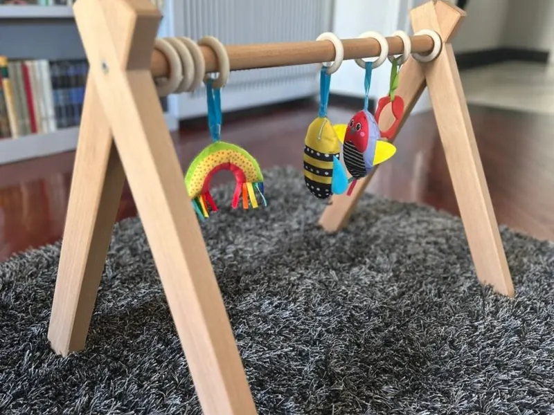 Palestrina montessoriana in faggio con giochi appesi, su un tappeto